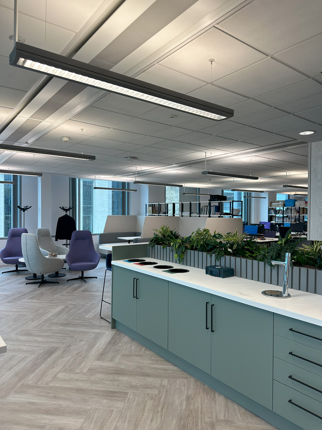 university office with the kitchen in the foreground in the background you can see the breakout spaces and the desks